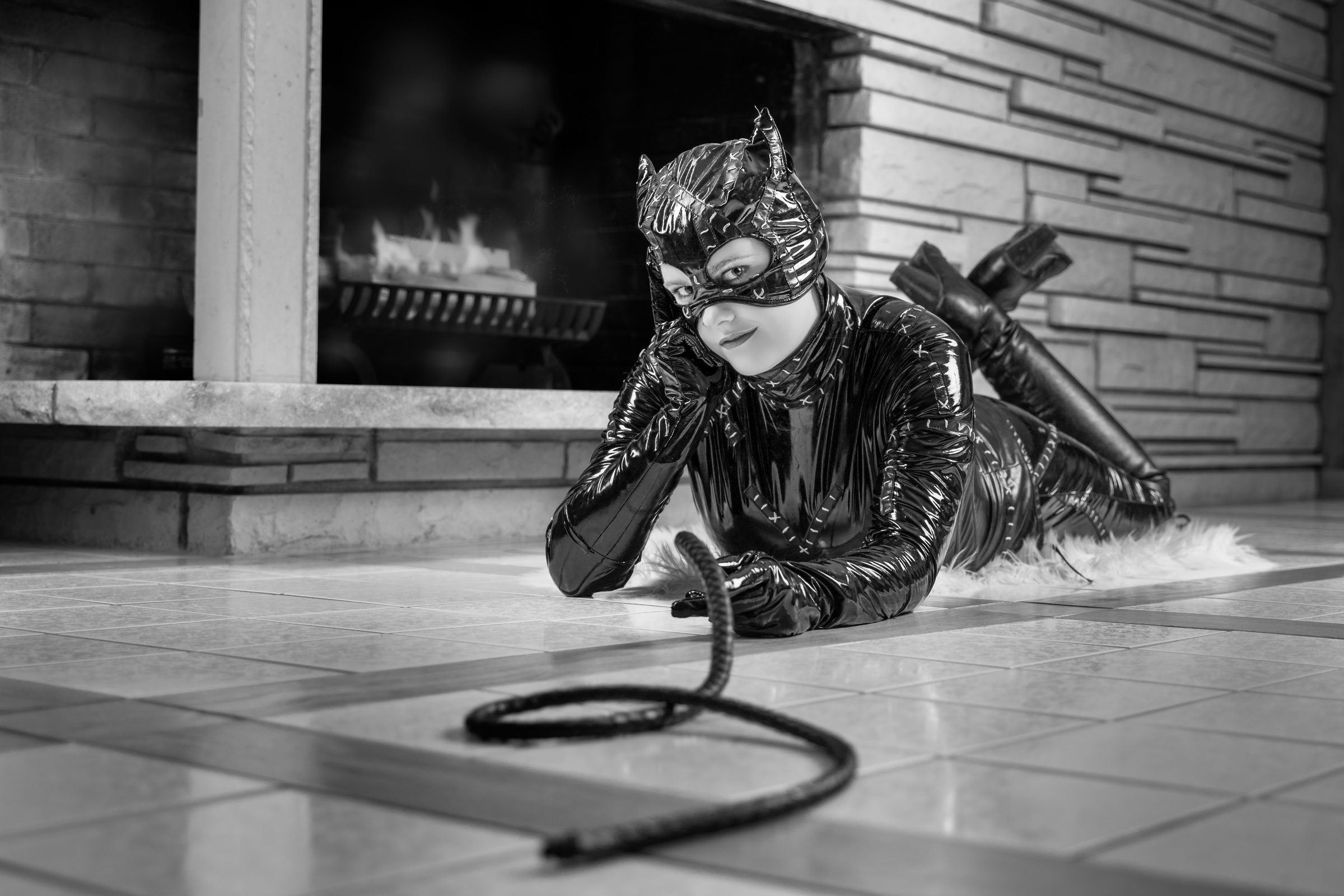Client in a black costume lying on the tile floor before the lit fireplace